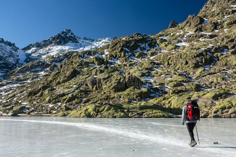 Gredos, Spain. 12-January-2019. Woman trekker walking above beautiful frozen lake during a sunny winter day stock photography Gredos, Spain. 12-January-2019. Woman trekker walking above beautiful frozen lake during a sunny winter day stock photography