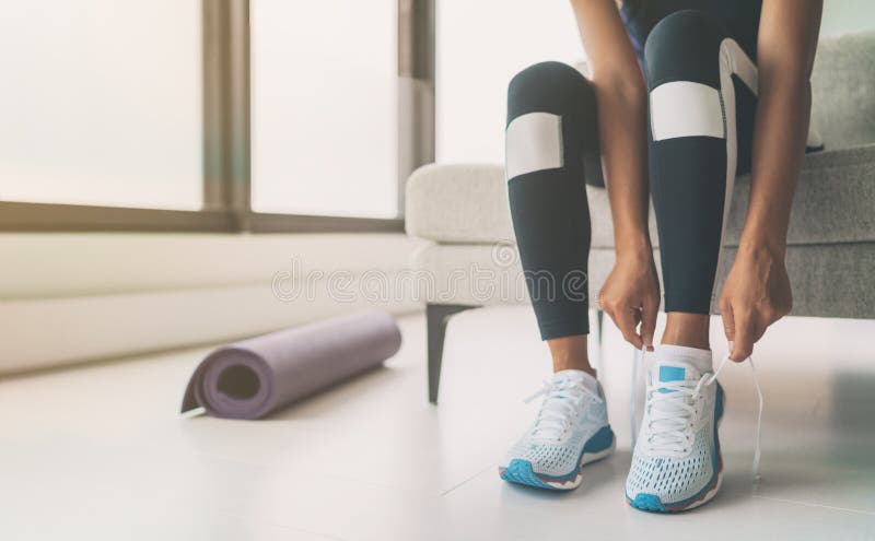 Woman tying running shoes laces getting ready to get back in shape going to yoga or pilates fitness class training at