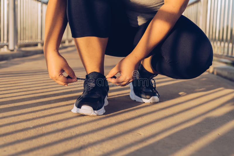 Woman tying shoelaces on a footbridge stock images