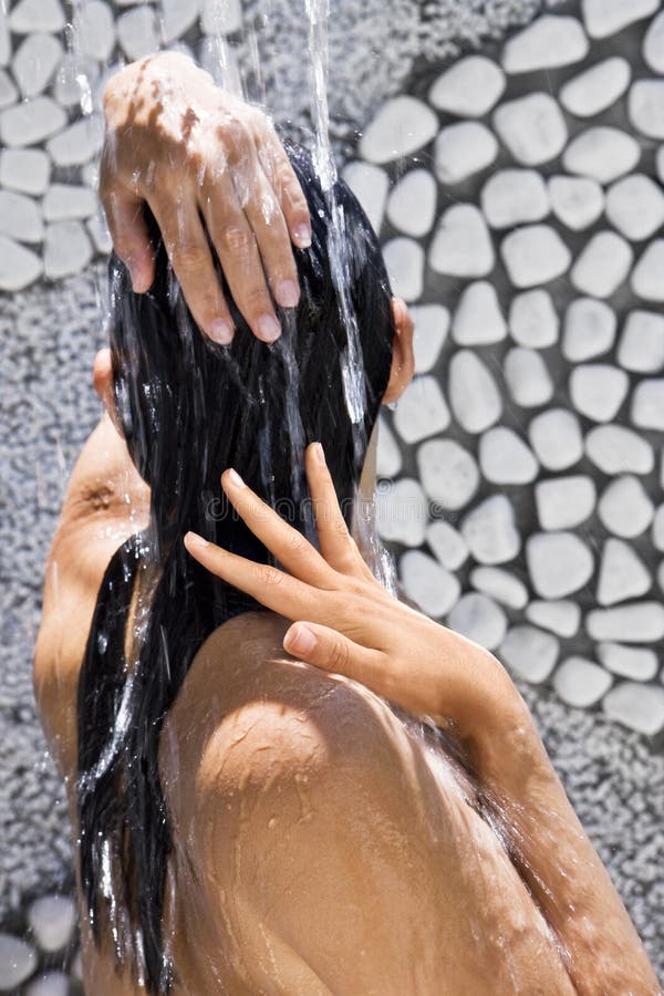 Donna sotto all'acqua per esterno, doccia, durante il trattamento nella spa.