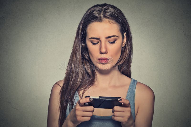 Portrét mladý žena nešťastný, naštvaný podle něco, někdo na její mobilní telefon textové zprávy, přijímání špatný zpráva šedá stěna.