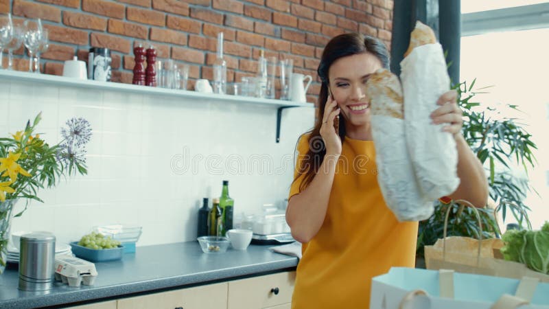 Woman unpacking shopping bags in kitchen. Housewife coming home after shopping.