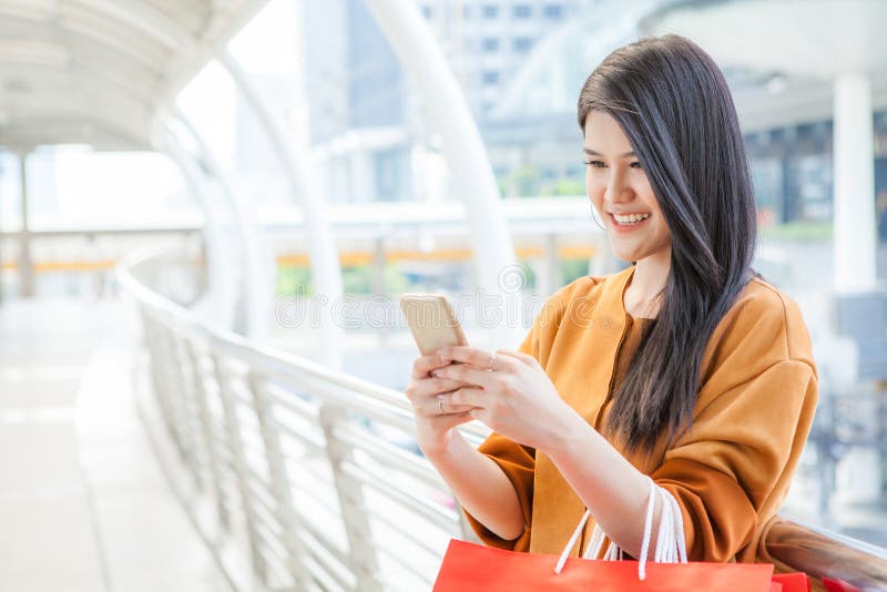 Woman use of mobile phone and carrying paper bags in city royalty free stock photography Woman use of mobile phone and carrying paper bags in city royalty free stock photography