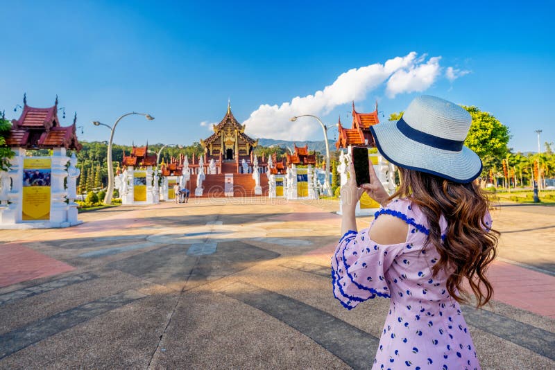 Woman use mobile phone take a photo at Ho kham luang northern thai style in Royal Flora ratchaphruek in Chiang Mai,Thailand.