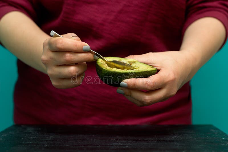 Woman Use Spoon To Scoop the Avocado Out of the Shell Stock Photo
