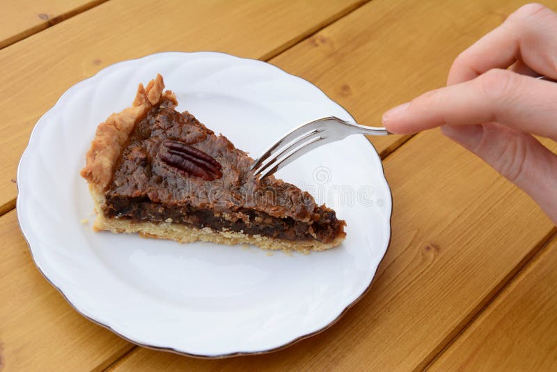 Woman Uses Dessert Fork To Cut into a Slice of Pecan Pie Stock Photo