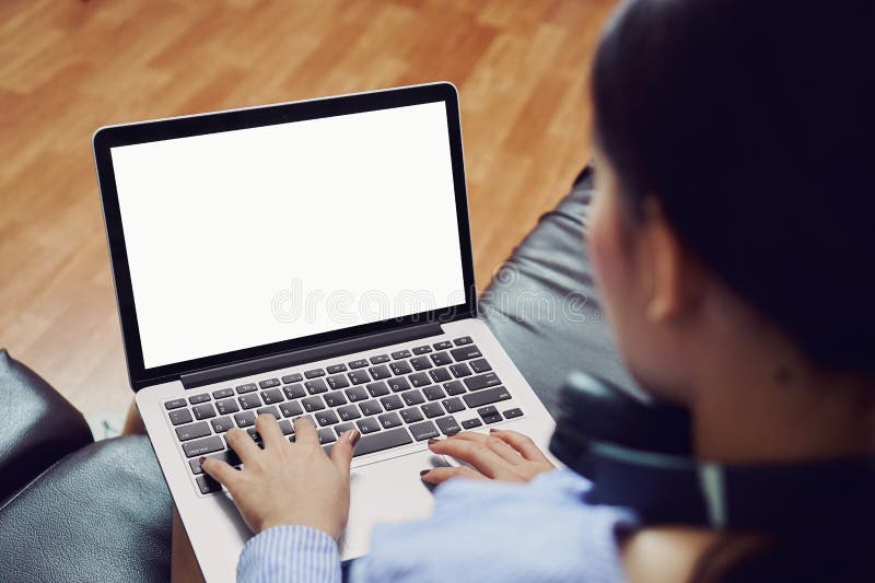 A woman uses an empty laptop screen in a room on a black sofa. royalty free stock photo