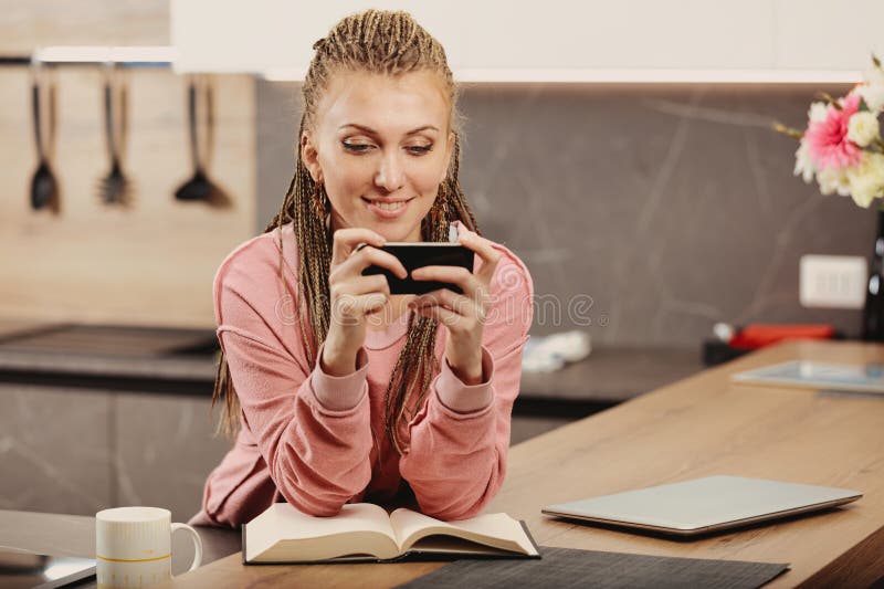 Woman uses phone, laptop for work, leisure, notes pitfalls royalty free stock photography