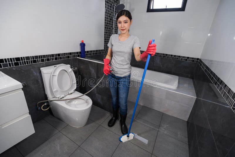 Woman using brush to cleaning the tile in bathroom stock photography Woman using brush to cleaning the tile in bathroom stock photography