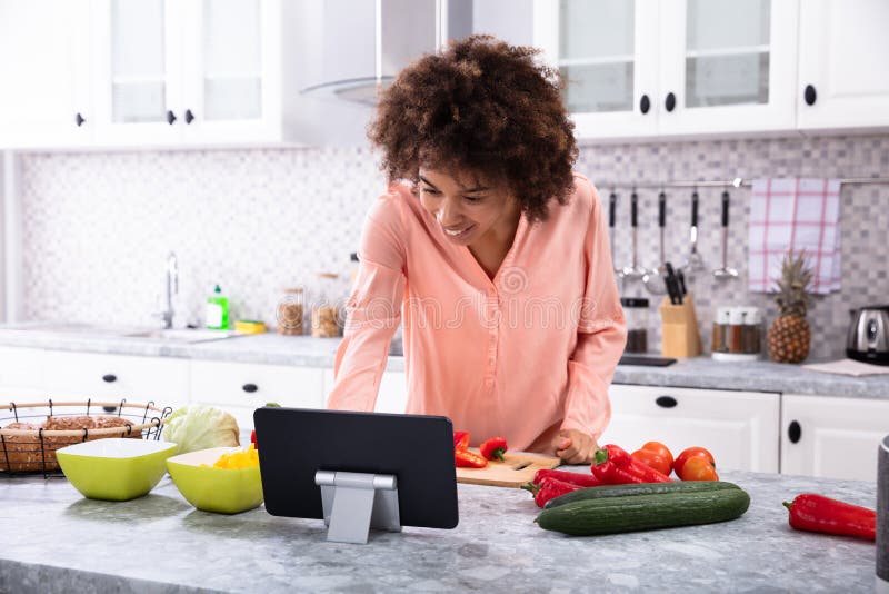 Woman Using Digital Tablet In Kitchen stock photography Woman Using Digital Tablet In Kitchen stock photography