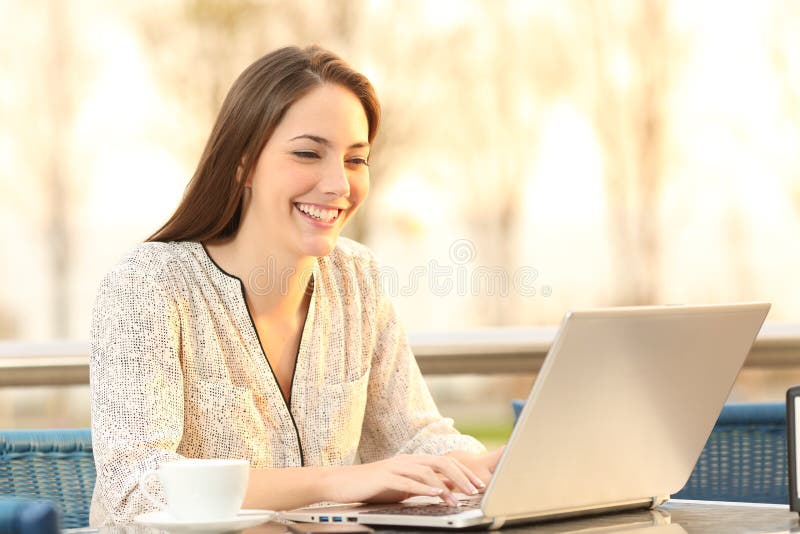 Woman is using a laptop in a coffee shop at sunset stock photography Woman is using a laptop in a coffee shop at sunset stock photography
