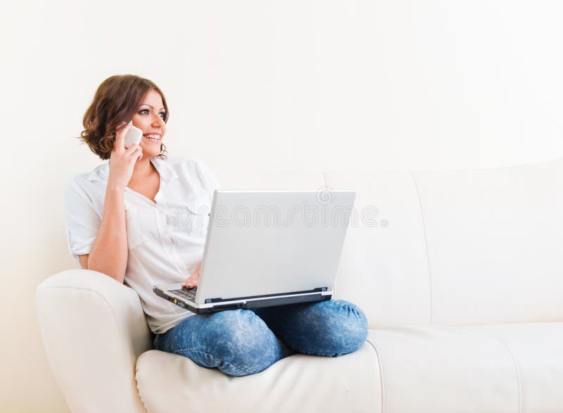 Woman Using Laptop and a Phone on the Sofa Stock Image - Image of ...