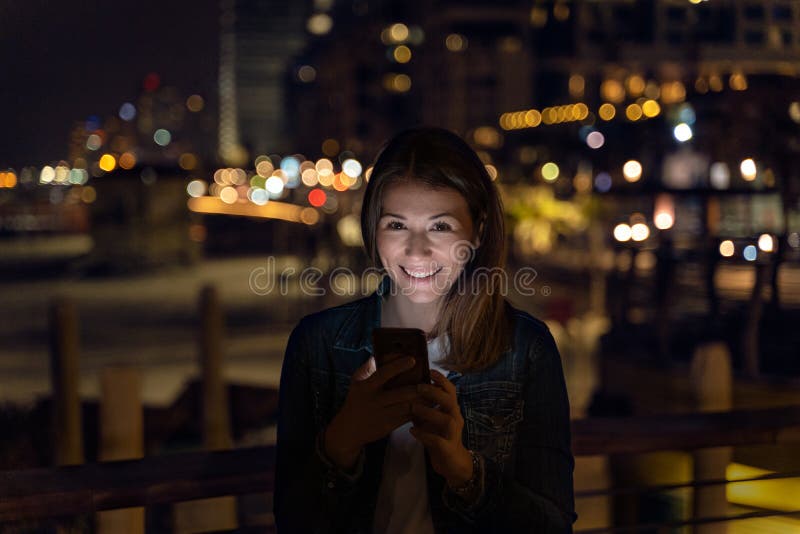 Young woman using her smartphone during the night. city light as background royalty free stock photos Young woman using her smartphone during the night. city light as background royalty free stock photos