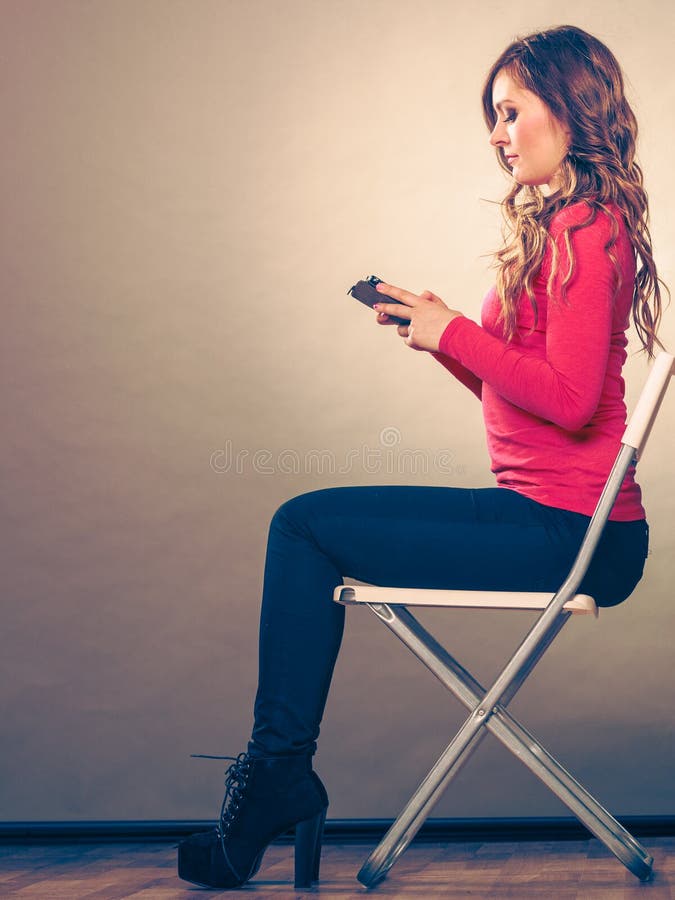 Woman using mobile phone sitting in chair. stock photos
