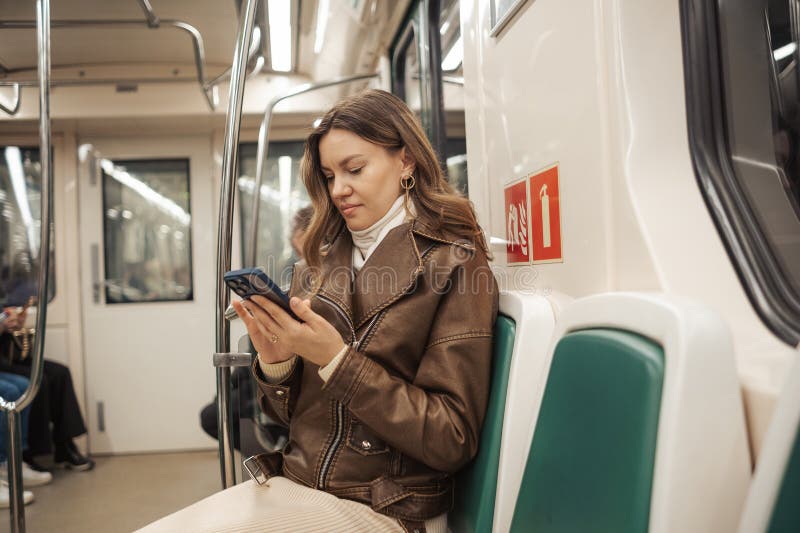 Woman Using Smartphone on Train During Morning Commute in Urban Environment royalty free stock image
