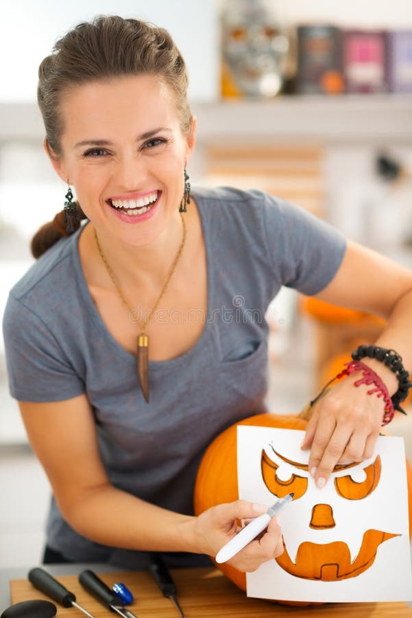 Woman Using Stencils To Carve Pumpkin Jack O Lantern Stock Photo woman-using-stencils-to-carve-pumpkin-jack-o-lantern-stock-photo