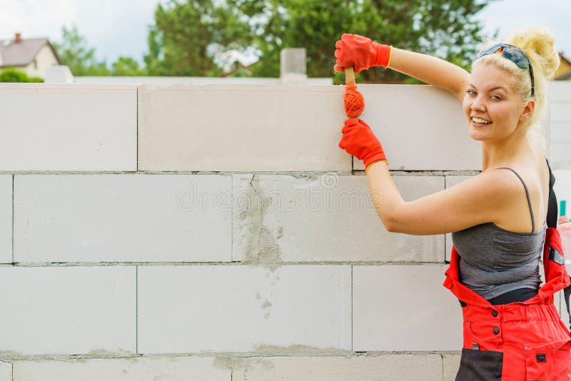 Woman using string as level in wall construction stock photo
