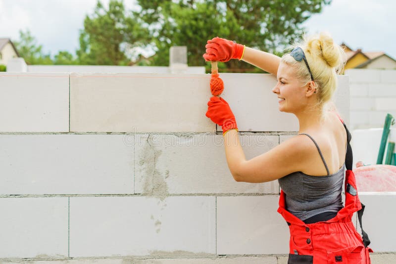 Woman using string as level in wall construction stock images