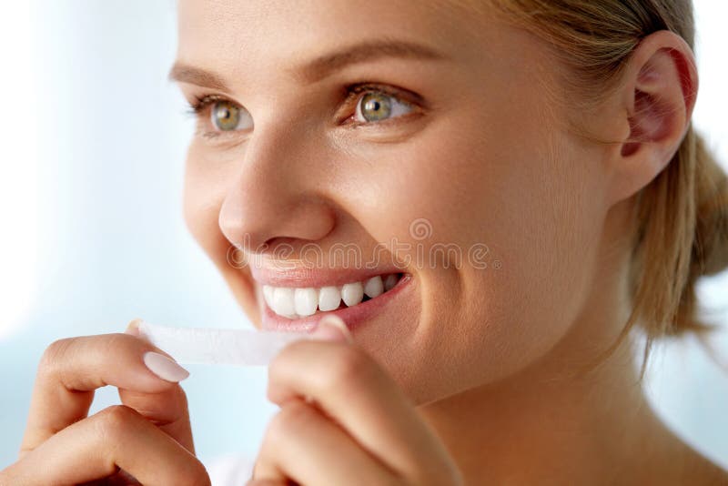 Woman Using Teeth Whitening Strip For Beautiful White Smile Stock Photo