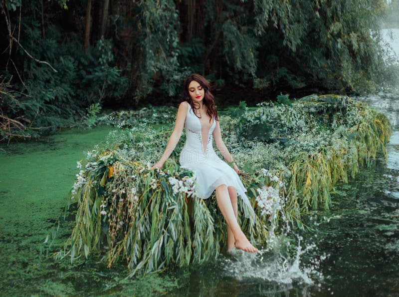 Woman in a vintage outfit sits on a boat and splashes her bare feet in water