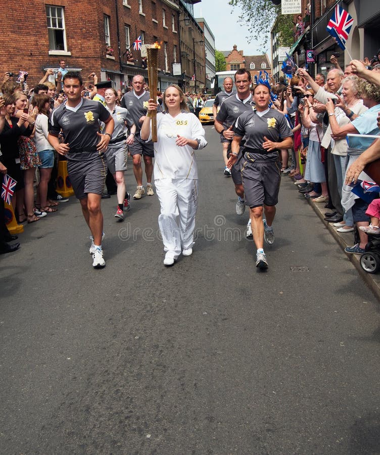 Young woman volunteer carrying the Olympic flame through the historic market town of Shrewsbury on May 30th 2012, cheered on by a large crowd of supporters. Shropshire, England. Young woman volunteer carrying the Olympic flame through the historic market town of Shrewsbury on May 30th 2012, cheered on by a large crowd of supporters. Shropshire, England.