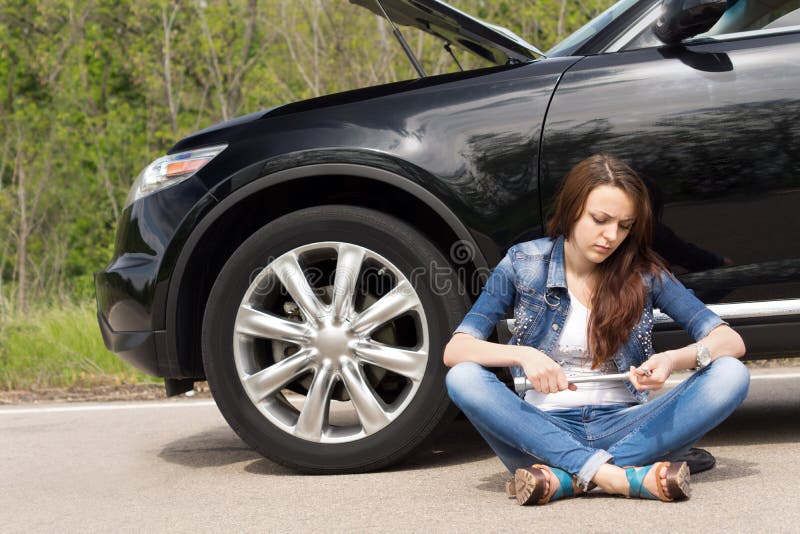 Woman waiting beside her broken down car