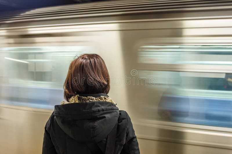 Woman Waiting at a Subway Station with a Train in Motion