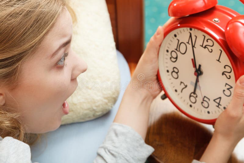Woman waking up late turning off alarm clock.