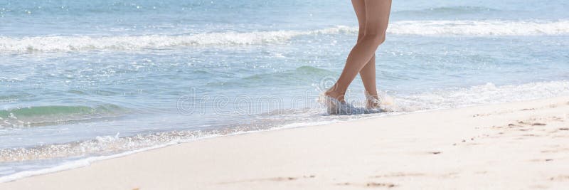 Woman walk on sea beach. Summer vacation, holidays, travel. Female barefoot feet walking ocean shore. Banner, copy space