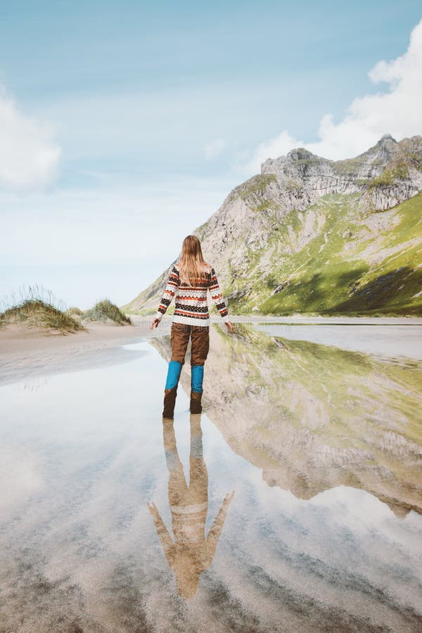 Woman walking alone outdoor water reflection mountain landscape travel in Norway