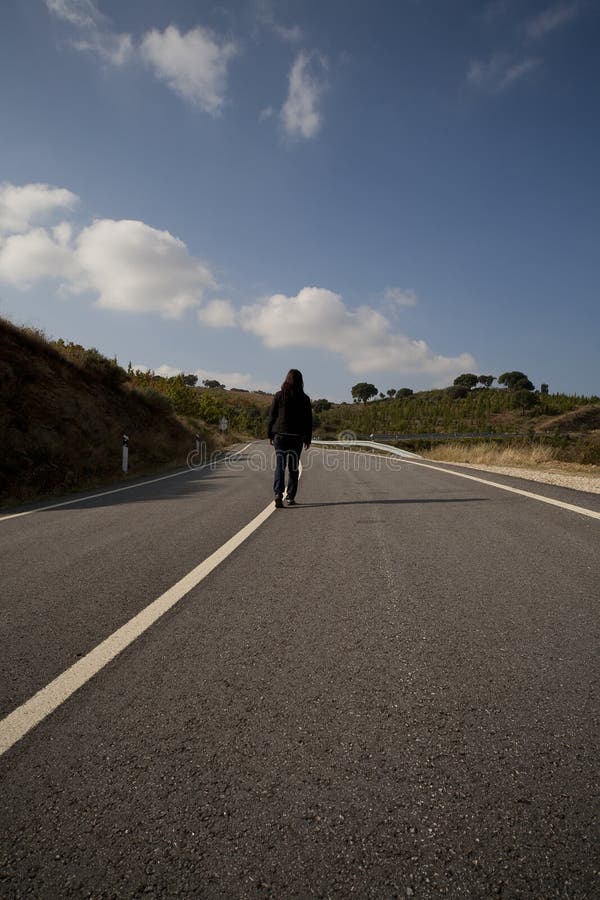 Woman walking on asphalt road