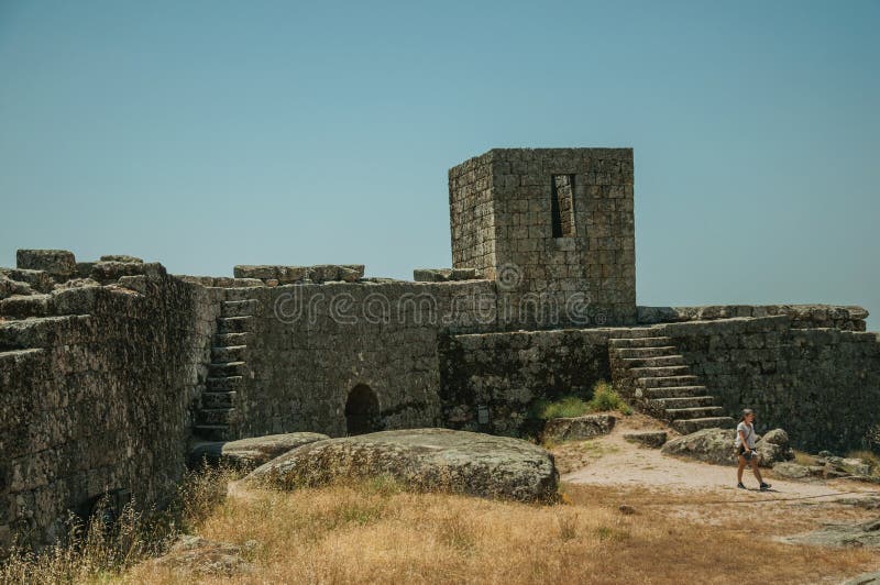 Woman walking in front of stone wall at the Castle of Monsanto stock image Woman walking in front of stone wall at the Castle of Monsanto stock image