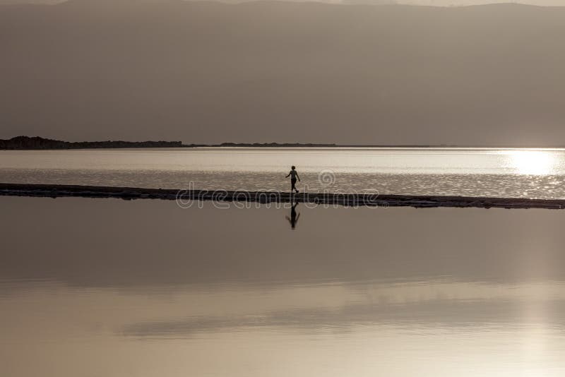 Woman walking on headland at early morning under rising sun