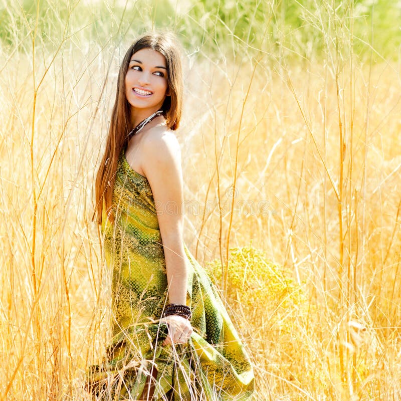 Asian indian woman walking outdoors in golden field with green long dress. Beautiful dried field flowers stock images, royalty-free photos and pictures