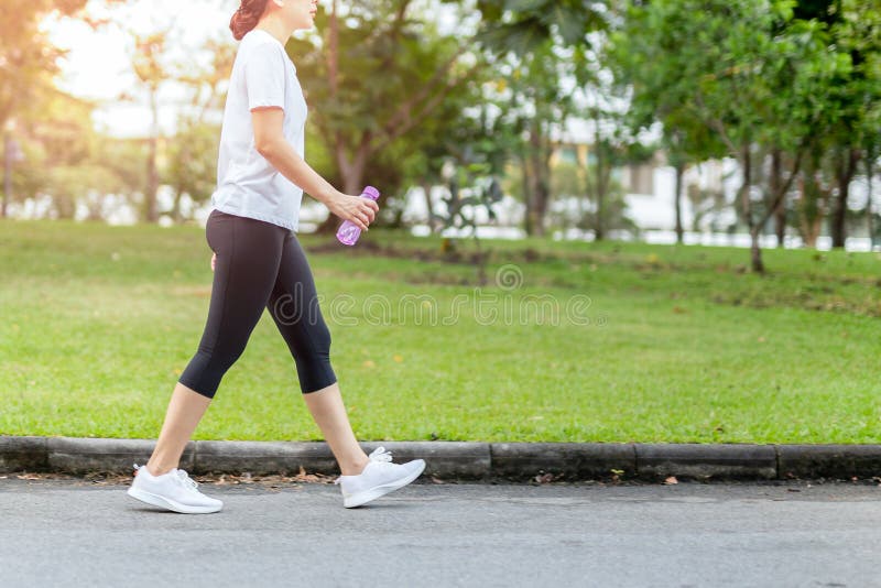 Woman walking in the park with bottle water in summer.