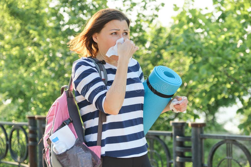 Woman walking in the park with handkerchief, coughing and sneezing stock photos Woman walking in the park with handkerchief, coughing and sneezing stock photos