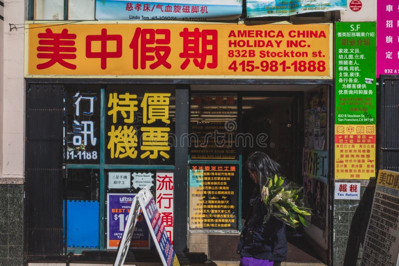 Woman Walking Past A Travel Agency With Signs In Chinese