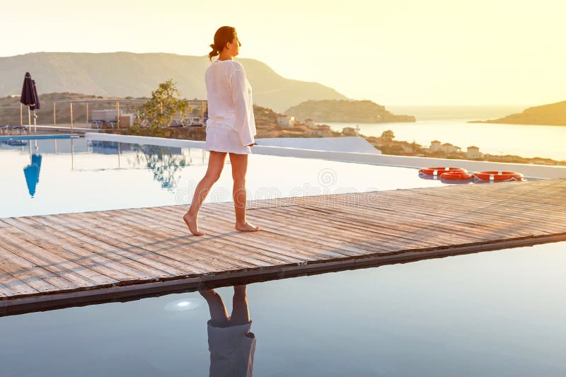 Woman walking at sunrise near swimming pool