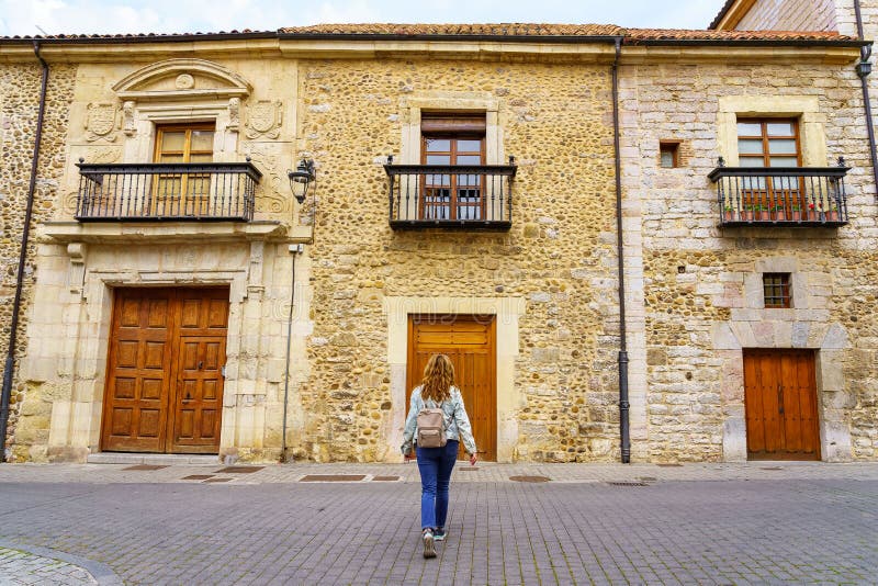 Woman walking to the door of an old and manor house in Leon, Spain.