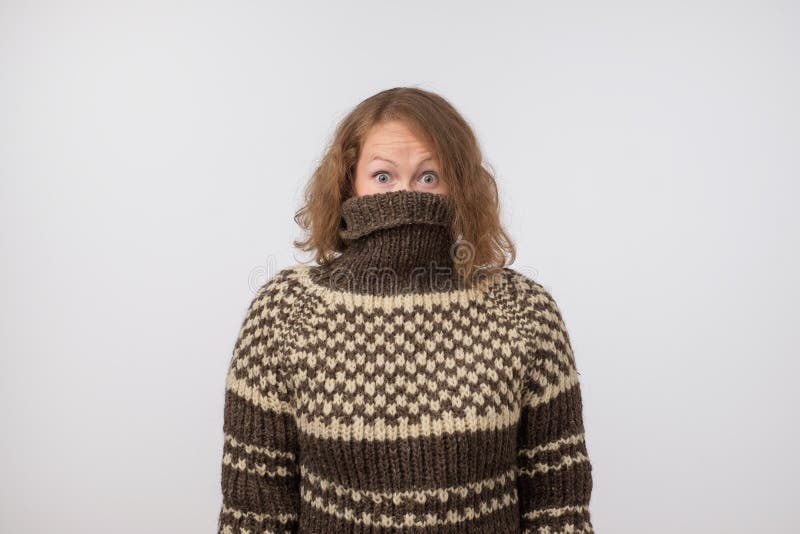 Woman in warm brown sweater hiding her face. Only eyes are seen. She wants to stay anonym. royalty free stock photo Woman in warm brown sweater hiding her face. Only eyes are seen. She wants to stay anonym. royalty free stock photo