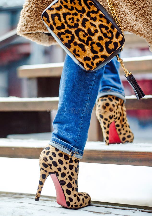 Woman warm fur coat in autumn or winter. Bag and boots in a leopard print. High heels. Fashionable bag close-up in female hands.
