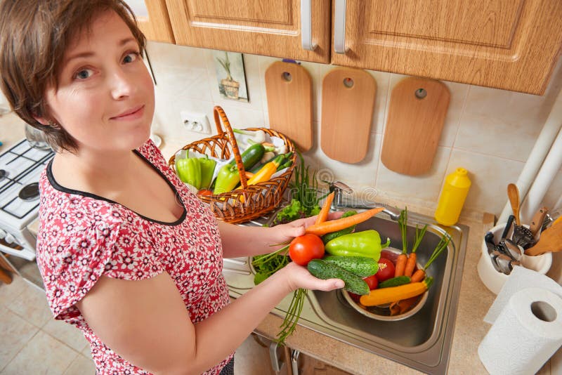 Woman wash vegetables and fresh greens in kitchen interior, healthy food concept