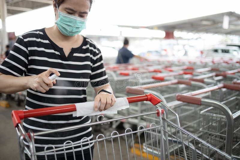 Woman wear mask,using spraying alcohol antiseptic,disinfecting spray,cleaning on shopping cart,trolley handle,protection during