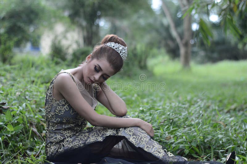 Woman Wearing Brown and White Sleeveless Floral Embroidered Dress Sitting on Green Grass Field royalty free stock image Woman Wearing Brown and White Sleeveless Floral Embroidered Dress Sitting on Green Grass Field royalty free stock image