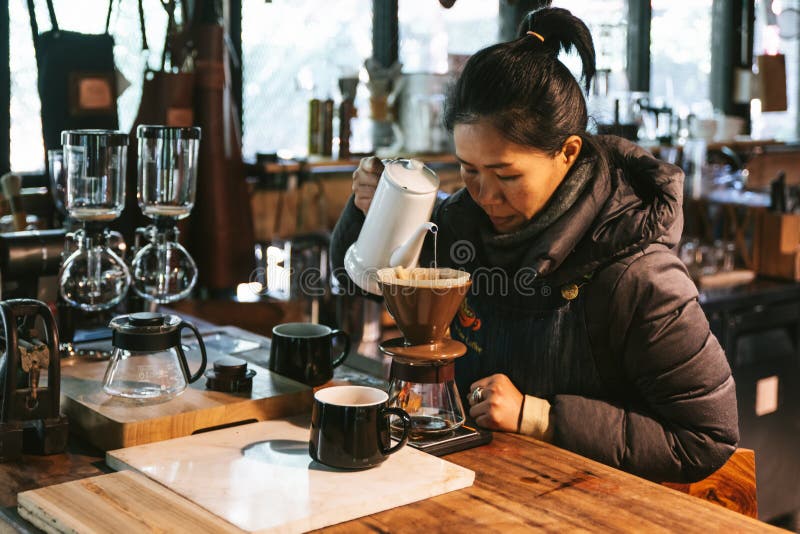 Woman wearing coat and making pour-over coffee with alternative method called Dripping. stock photography Woman wearing coat and making pour-over coffee with alternative method called Dripping. stock photography