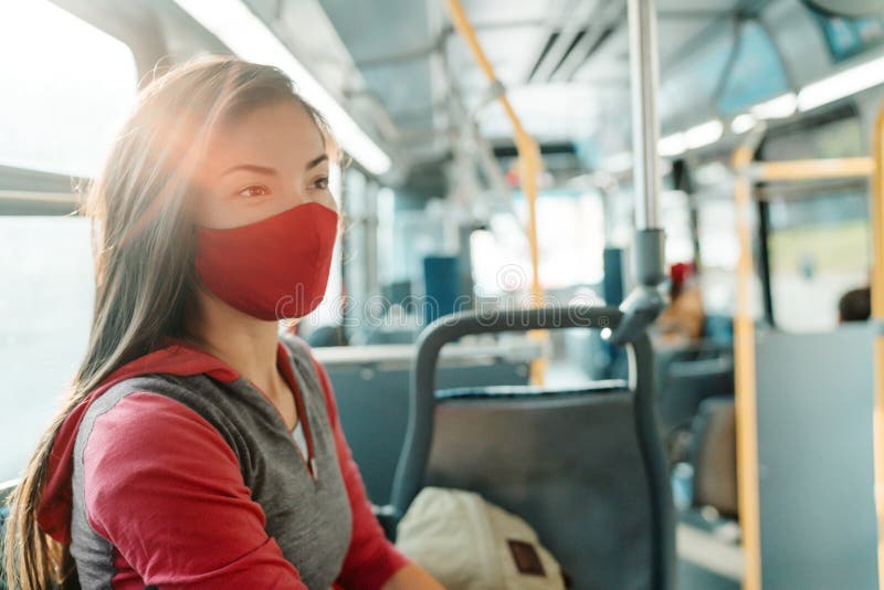 Woman wearing face mask inside public transport bus commuting to work. Asian girl passenger sitting with red facial stock photo Woman wearing face mask inside public transport bus commuting to work. Asian girl passenger sitting with red facial stock photo