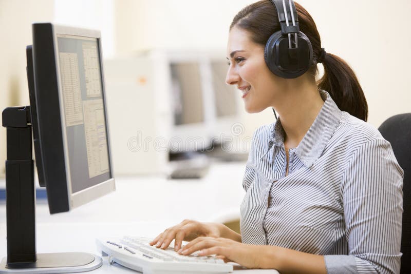 Woman wearing headphones in computer room typing