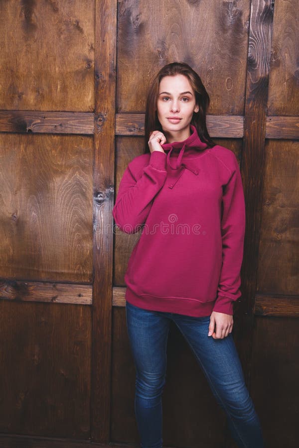 Woman wearing magenta sweatshirt in front of wooden wall