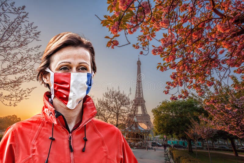 Woman wearing protection face mask with French flag against coronavirus in front of the Eiffel Tower in Paris, France