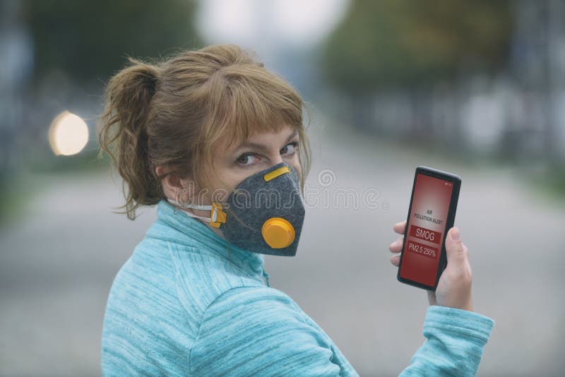 Woman wearing a real anti-smog face mask and checking current air pollution with smart phone app stock photography Woman wearing a real anti-smog face mask and checking current air pollution with smart phone app stock photography